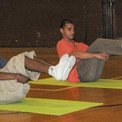Two students perform a floor pose, practicing both balance and strength.