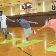 Four students practice balance, leaning forward on one leg, arms out.