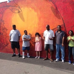 Participants stand in front of an orange graffiti style painted wall.