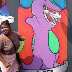 A participant takes a picture in front of a graffiti of Barney.