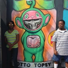 Participants pose around a graffiti of a Telly Tubby.
