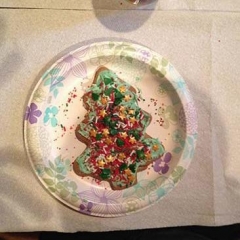 A plate with a Christmas Tree cookie decorated with sprinkles.