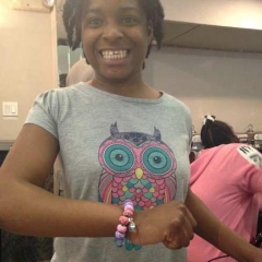 A smiling participant showcasing a bracelet she just made in the art class.