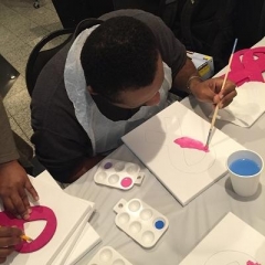 A participant is painting a pink ribbon.
