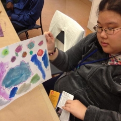 A participant showing her painting for the camera.