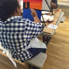 Participant painting a building against an orange sky in the background.