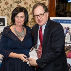 Sophia Rossovsky hands an award to Andy Fisher, Director of Lavelle Fund for the Blind.  ID: Sophia and Andy are holding a crystal award.