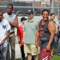 A group of participants gathered on a baseball field.  ID: Participants are wearing sport clothing.