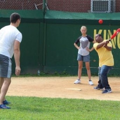 A participant hits a ball with a baseball bat.  ID: The picture captures the ball in the air.
