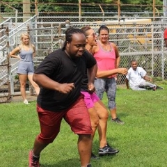 A participant is running through a ballpark.  ID: A participant is wearing red and black.