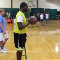 Participant preparing for a freethrow.  ID: A participant wearing a bright yellow jersey is getting ready to make a shot.