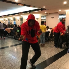 A participant poses as Spider Man.  ID: A participant is wearing a red sweatshirt with a picture of a spider on it.