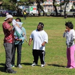 Participants playing with a kite.  ID:  One participant is holding up a kite while another three observe.