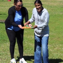Participants smiling for the camera.  ID: Two participants standing in the grass.