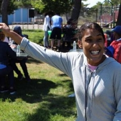 A participant holding up a toy.  ID: A participant is wearing a gray t-shirt.