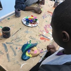 A participant paints a figure made out of clay.