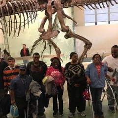 The group poses in front of a dinosaur display at the Museum of Natural History.