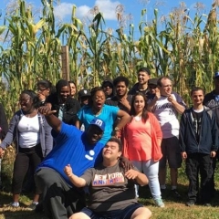 Participants at Decker Farms.  ID: A group of participants standing in a corn field.