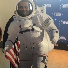 Participant at a Liberty Science Museum.  ID: A participant is wearing a space flight suite.