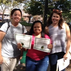 Day Habilitation participant holds up an award she received for participating in Therapeutic Garden Project for People of All Abilities.  ID: The participant is wearing a bright pink shirt.