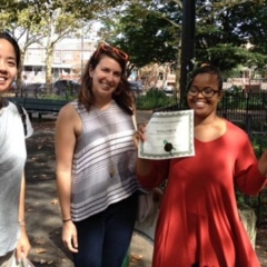 Day Habilitation participant holds up an award she received for participating in Therapeutic Garden Project for People of All Abilities.  ID: The participant is wearing a red dress.