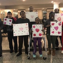 Participants hold up their Valentine's Day artwork.