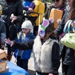 A girl reaching for the treasure chest.  ID: The girl is wearing Easter Bunny mask.