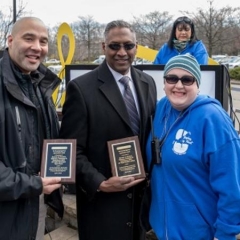 ATF agents receive an award for their help with the Beeping Eggs.  ID:  Two ATF agents stand with Holly Bonner, the Director of Accessibility for City Access New York.