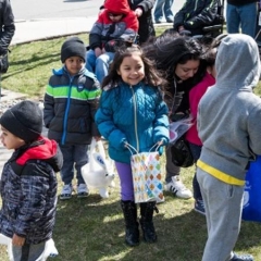 Kids waiting for the Easter Egg hunt to begin.  ID: A group of kids on the grass.