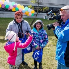 A little girl being interviewed.  ID: A girl is holding up her hand to wave at the camera man.