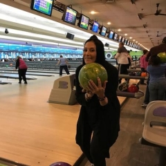 Ilene Rosen, the event organizer, is getting ready to bowl.  ID: Ilene is holding up a green bowling ball.