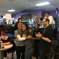 Attendees hug and clap to celebrate a strike.  ID: Four attendees smiling.