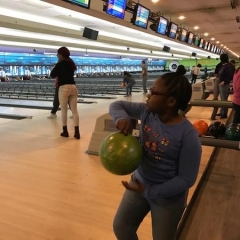 A participant prepairing to bowl.  ID: A participant is holding a green bowling ball.