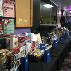 Raffle display.  ID: Raffle Table featuring various baskets prizes on a black tablecloth.