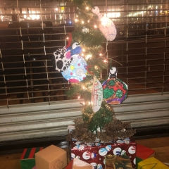 A Christmas Tree made by City Access participants out of recyclable materials.  ID:  The tree is covered by colorful ornaments.