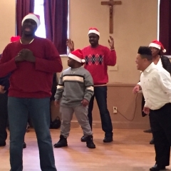 Participants perform a dance.  ID: Wearing red and white Santa hats, participants perform a dance.