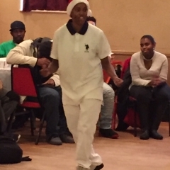 A participant in the middle of a dance.  ID: Participant dressed in all white.