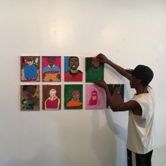 A participant is putting up a display of self portraits at  The Living Gallery in Brooklyn.