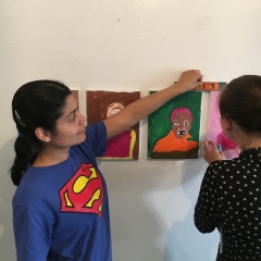 Participants are putting up a display of self portraits at  The Living Gallery in Brooklyn.