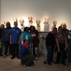 Participants grouped together for the picture.  ID: Standing in front of head sculptures.