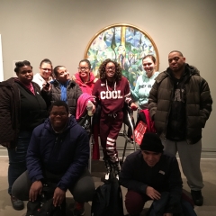 Participants smile for the camera.  ID: Standing in front of an exhibit.