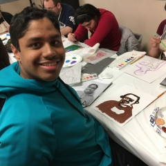 Participants working on their self portraits.  ID: In the center, a participant smiles for the camera.