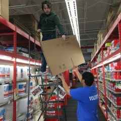 Participants work together to restock shelves with cardboard boxes.