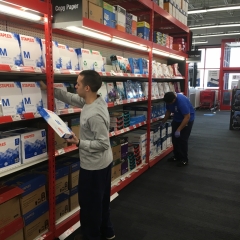 Participant is restocking printing paper aisle while working at Staples.